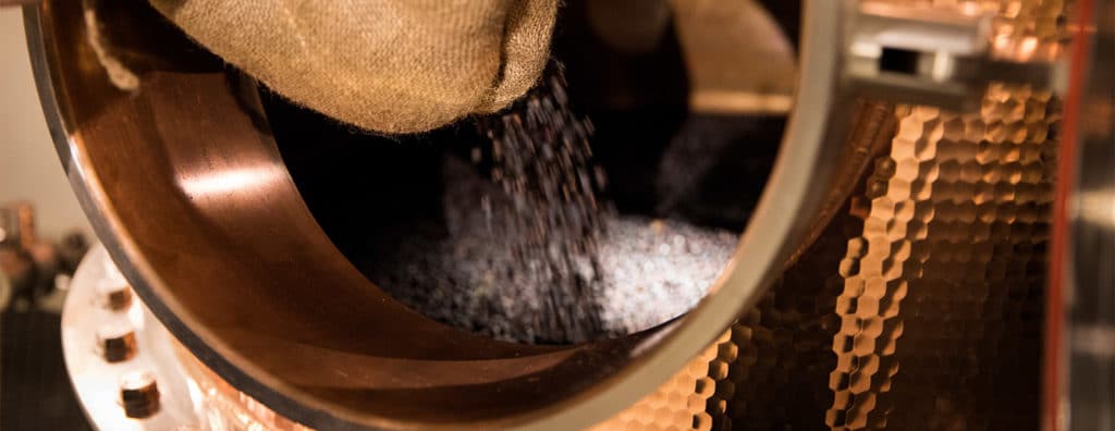 Juniper berries being put into a still